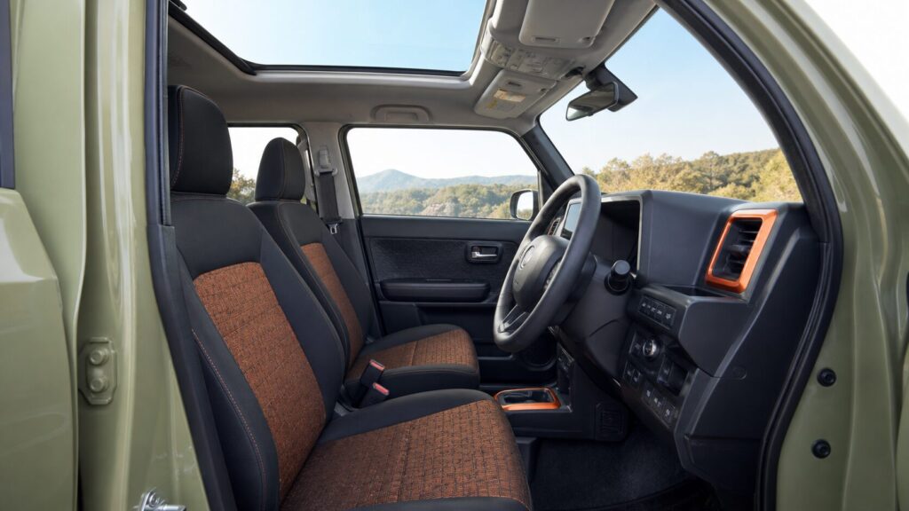 Interior of a TAFT from the driver door opening, dashboard and front seats with orange fabric accents against